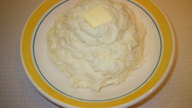 Garlic mashed potatoes in a bowl and topped by a square of butter