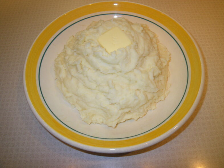 Garlic mashed potatoes in a bowl and topped by a square of butter